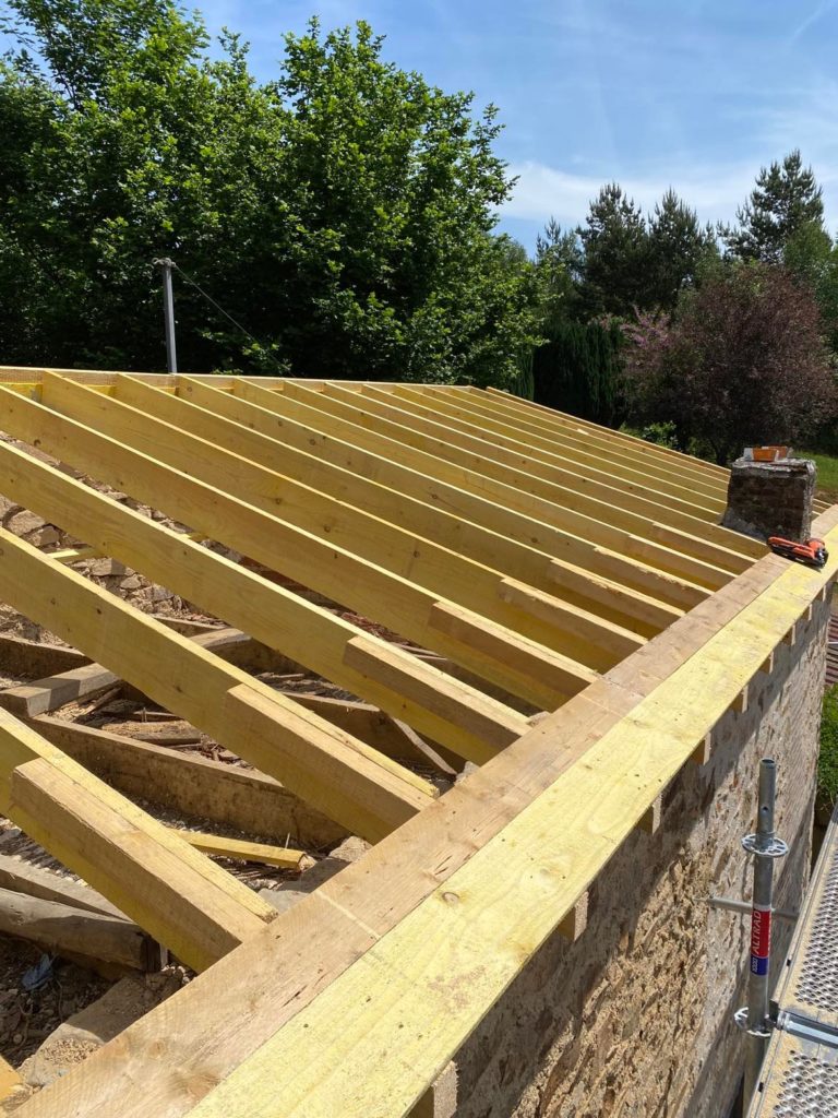 Charpente en bois en cours d'installation sur une toiture lors d'une rénovation effectuée par DGC Couverture.