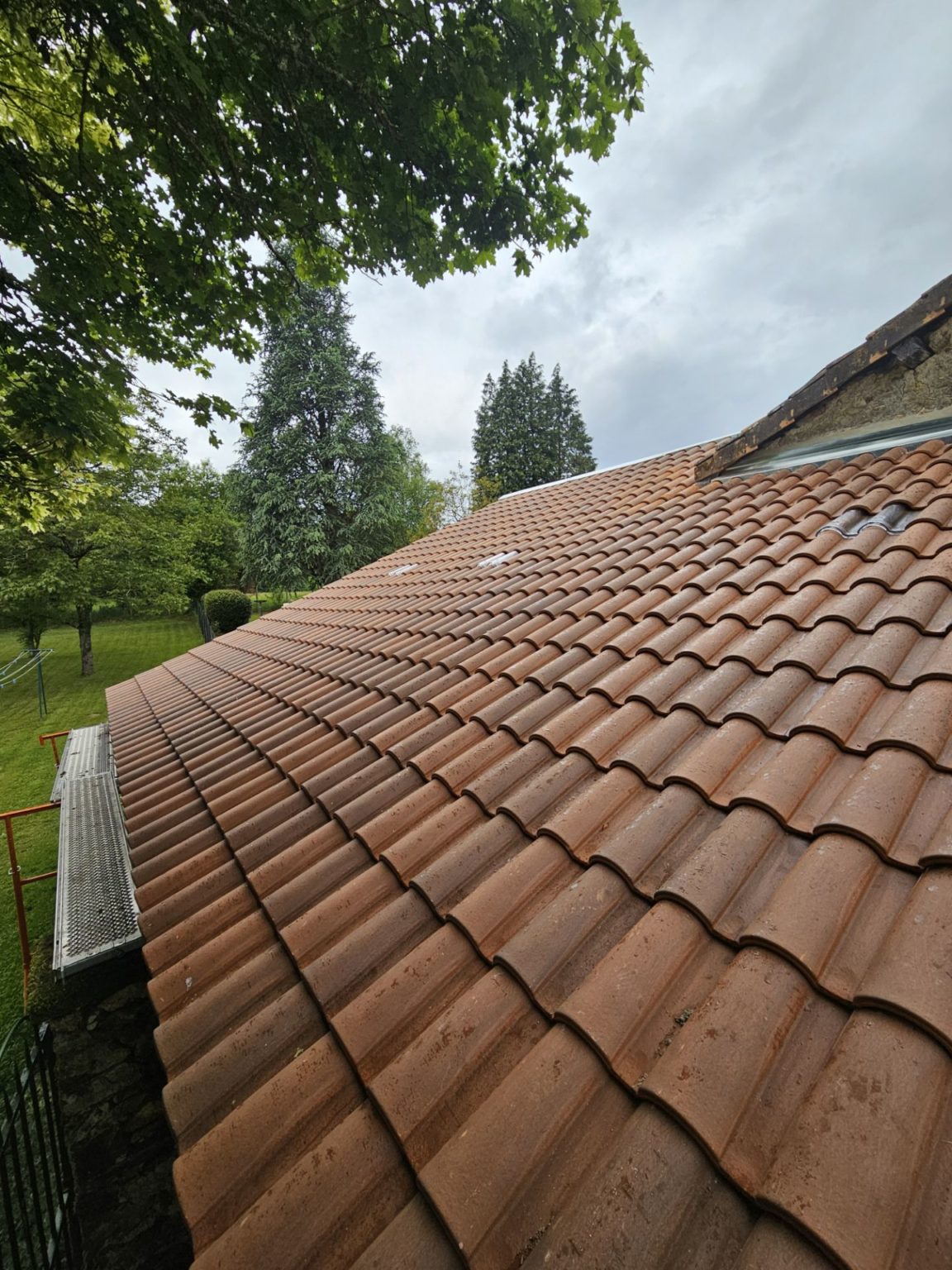 Toiture en tuiles terre cuite rénovée à Limoges (87), versant en pente avec gouttière zinc, vue de près après pluie