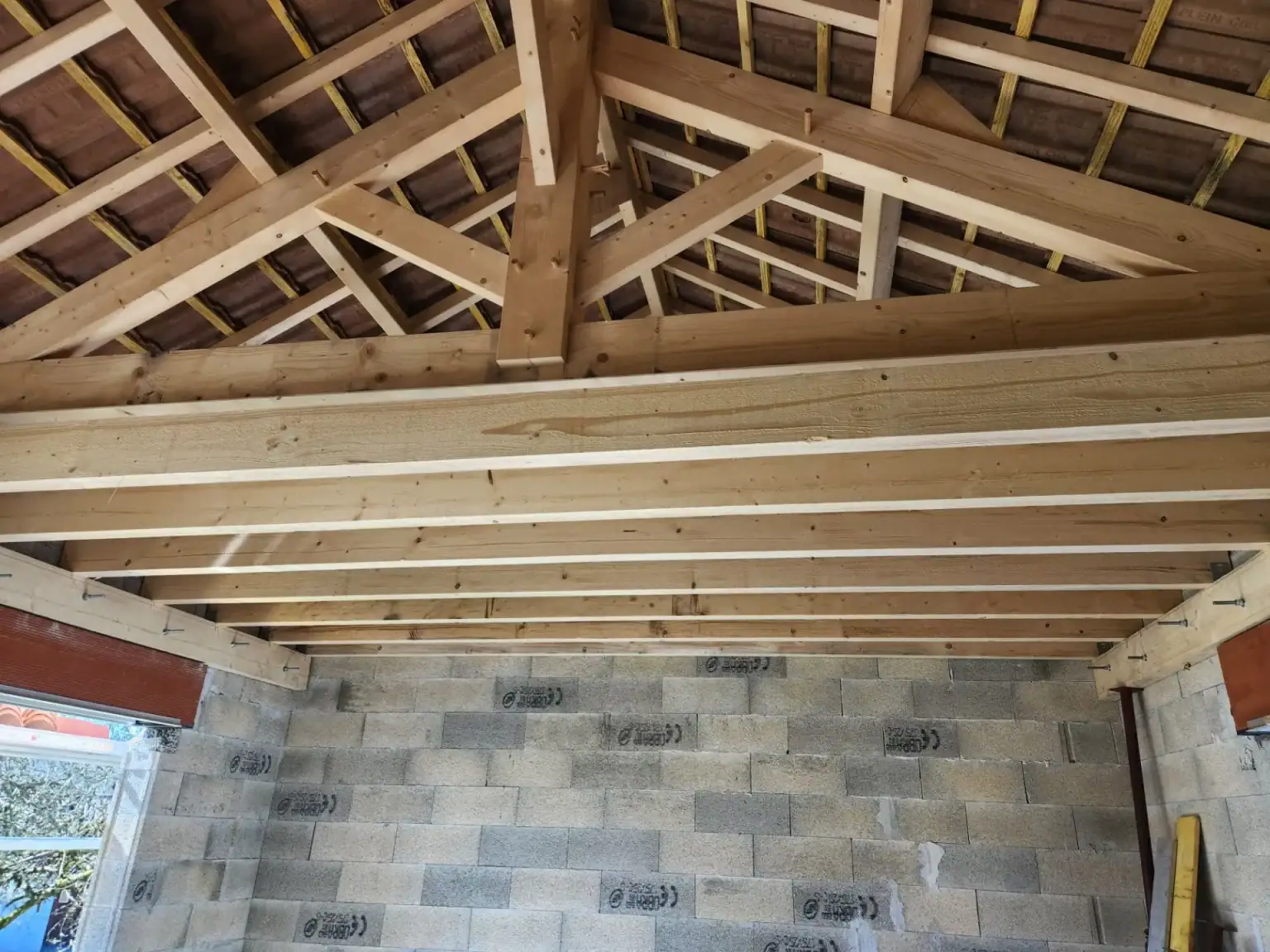 Charpente traditionnelle en bois réalisée sur un chantier à Limoges, avec poutres apparentes et structure de toiture soignée.