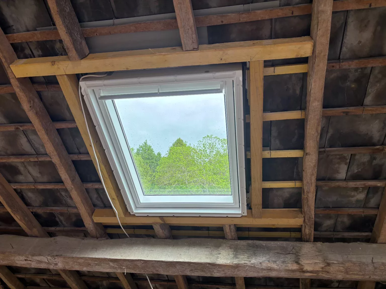 Fenêtre de toit installée sur une toiture existante à Limoges, avec encadrement bois et charpente apparente.